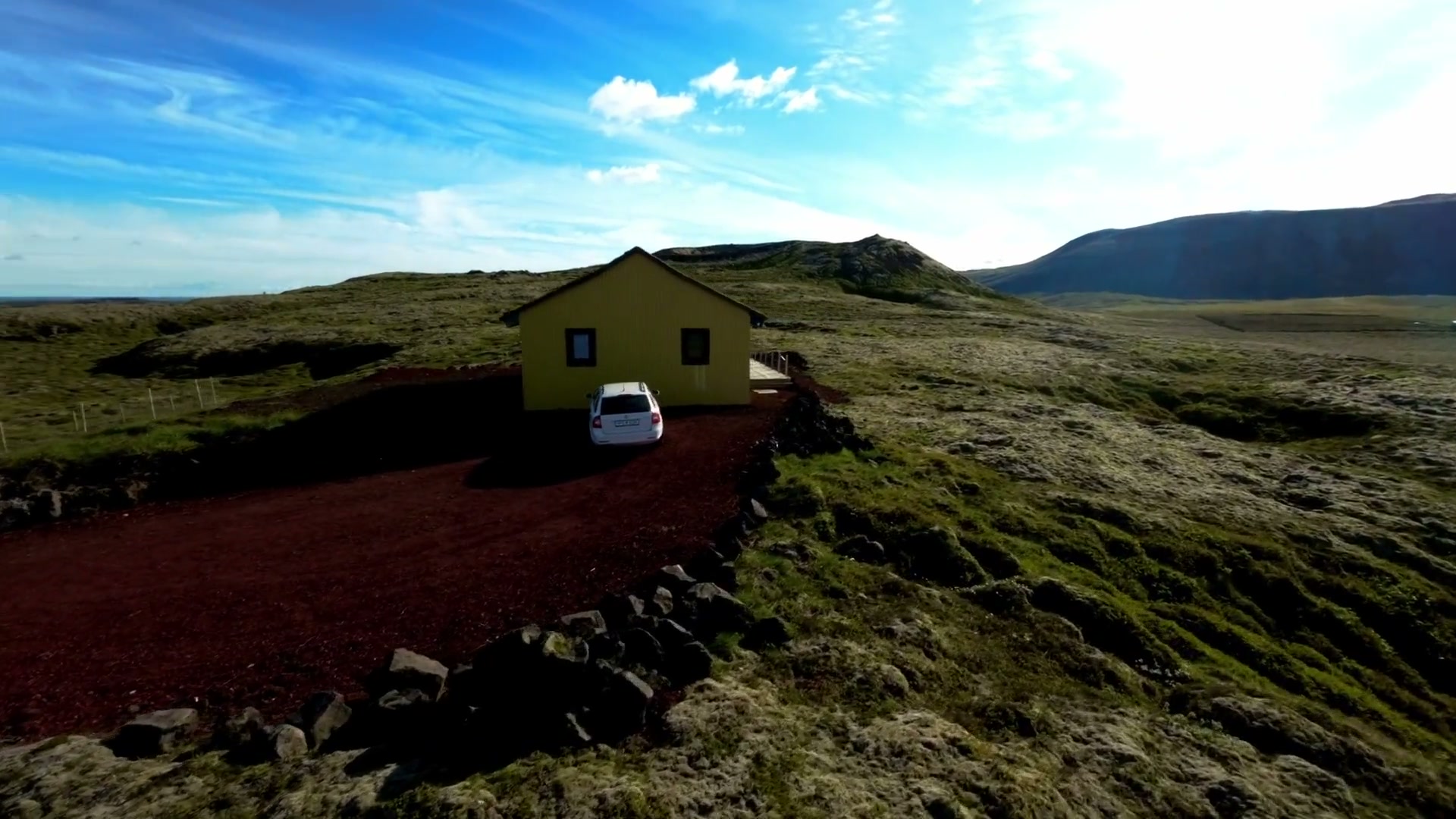 Casa Lumière — the house at the end of its red gravel drive, mountain ridge behind