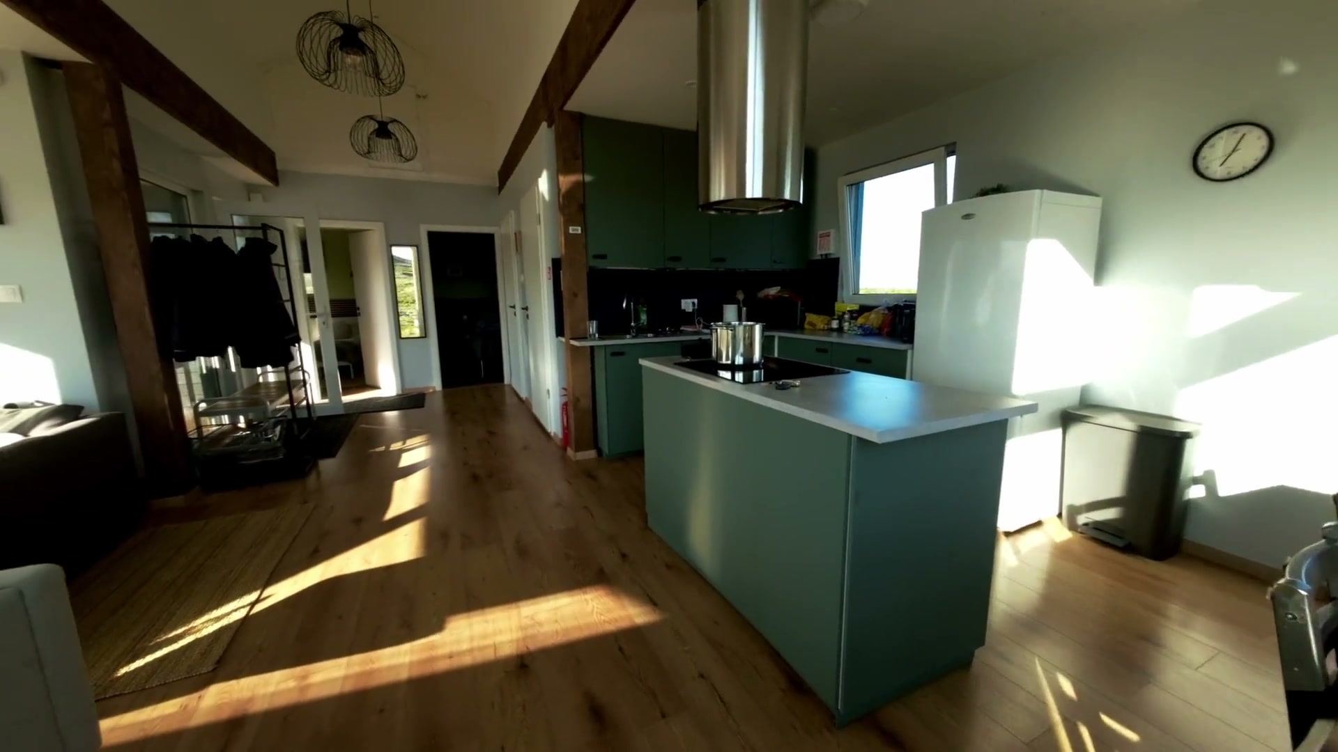 The kitchen — sage-green cabinetry and island beneath a steel hood